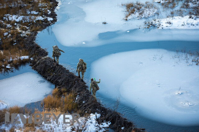 Hunters hiking across a beaver dam