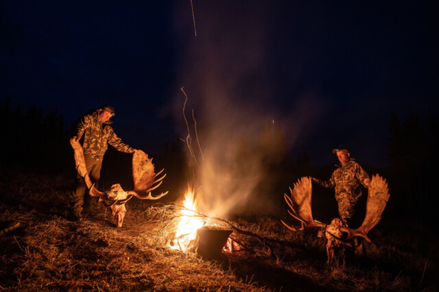 Successful moose hunters around a campfire.